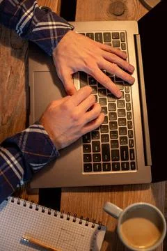 Young man drinking coffee in cafe and using laptop. Man's hands using laptop Stock Photos