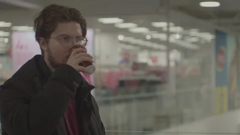 Young man drinking coffee indoors. In mall Stock Footage 265573881