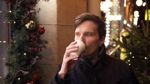 Young man drinking coffee outdoors on city street at night. Stock Footage 83630613