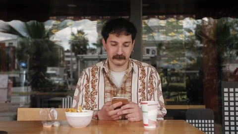Young man drinking coffee scrolling browsing using smartphone. Stock-Footage 292009988