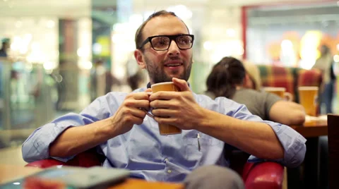Young man drinking coffee in the shopping mall Stock Footage 37025840