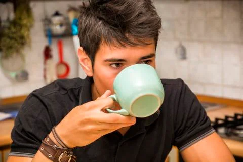 Young Man Drinking Coffee Sitting at Kitchen Table Stock Photos