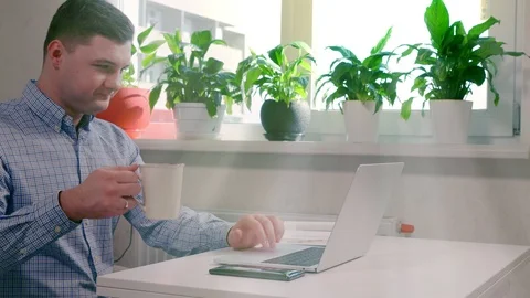 Young man drinking coffee while working on laptop Stock Footage 125897760