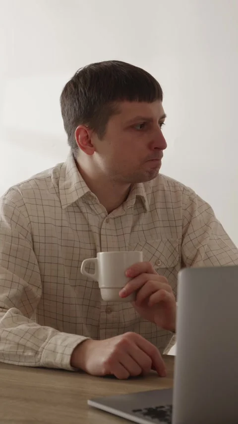 Young man drinking coffee while working on laptop at desk close up Stock Footage 335082320