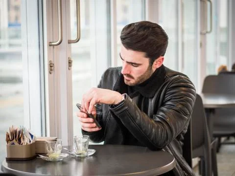 Young Man Drinking Coffee While Looking at Phone Stock Photos