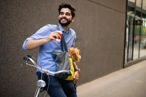 Young man drinking coffee while sitting on his bicycle with dog outdoors Stock Photos