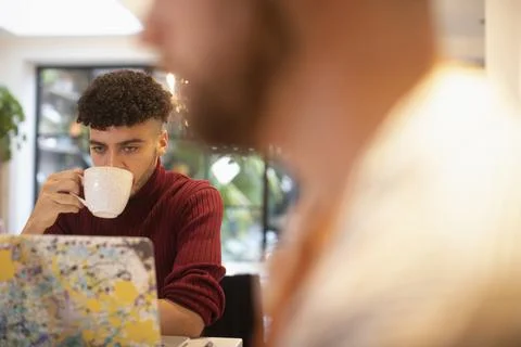 Young man drinking coffee working from home at laptop Stock Photos
