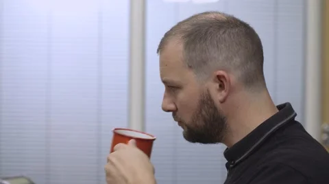 Young man drinking cup of coffee at his desk 스톡 동영상 68614943