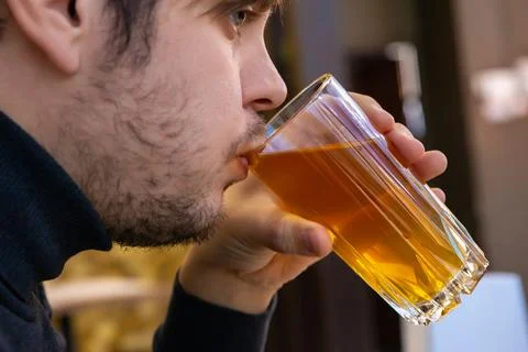 Young man drinking dried fruit compote from glass mug. Healthy drink Stock Photos