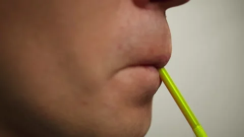 Young man drinking a drink from a plastic cocktail tube, close up Stock Footage 141683008