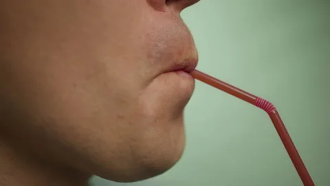 Young man drinking a drink from a plastic cocktail tube, close-up, side view Stock Footage 144567168