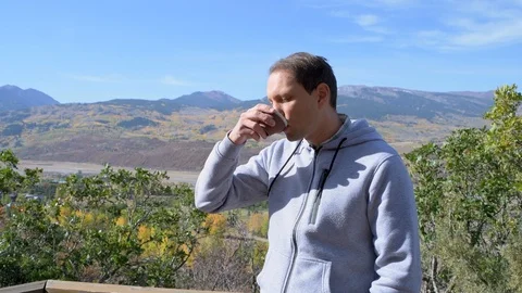 Young man drinking green tea with view of rocky mountains in Aspen, Colorado Stock Footage 120608302