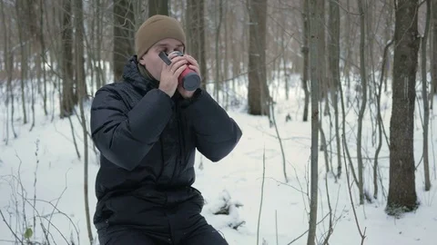 A young man drinking a hot beverage from a thermos in a winter forest. The man Stock Footage 71211563