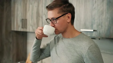 Young man is drinking hot strong coffee from a white cup. Stock Footage 144685980