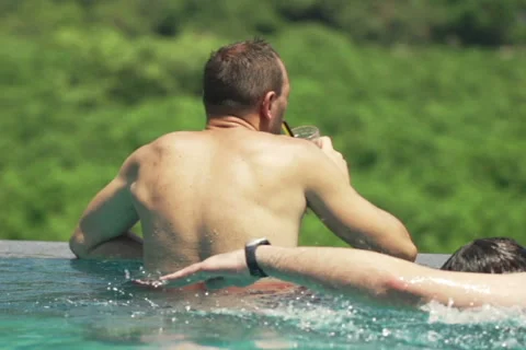 Young man drinking juice on swimming pool,  slow motion, shot at 240fps NTSC Stock Footage 56357053