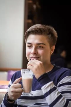Young man drinking latte or cacao from the tube Stock Photos
