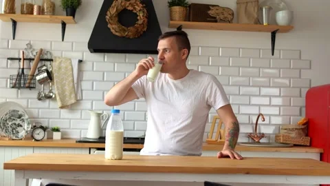 Young man drinking milk in kitchen. Adult male enjoying useful drink for Stock Footage 131862177
