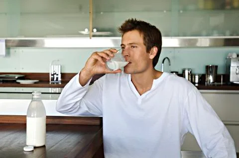Young man drinking milk in kitchen Stock Photos
