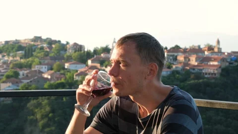 Young man drinking red wine on terrace at sunset Stock Footage 255732213