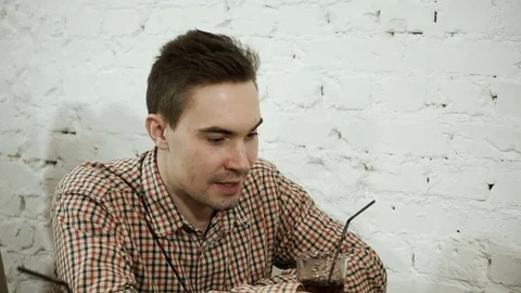 A young man drinking tasty beverage and talking with his friends in the cafe. HD 動画素材 74294304