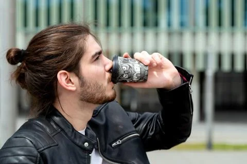 Young man drinking tea or coffee from a black disposable take-out paper cup Stock Photos