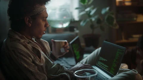 Young Man Drinking Tea from Paper Cup while Coding on Laptop Stock Footage 290873440