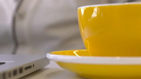 Young man is drinking tea while sitting at table with laptop in company. Video stock 87130819