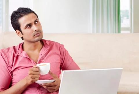 Young man drinking tea while using laptop Stock Photos