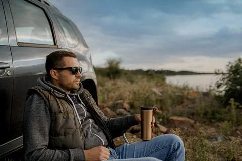 Young man is drinking tea while fishing. Outdoor picnic concept Stock Photos