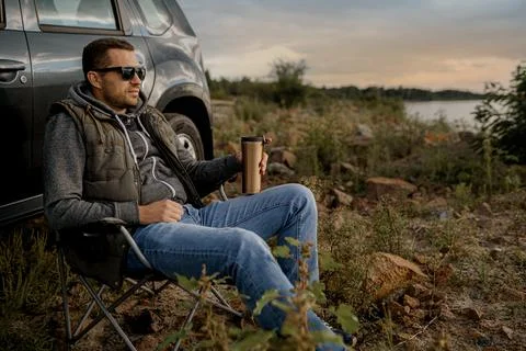 Young man is drinking tea while fishing. Outdoor picnic concept Stock Photos