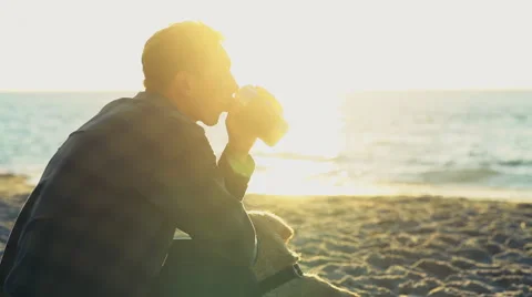 Young man drinking from thermocup on a beach slow motion Stock Footage 54635432
