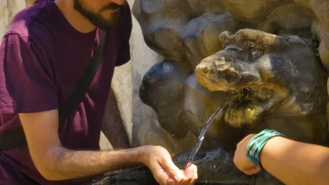 Young Man Drinking Water from ancient Fountain in a Park Rome Vídeo Stock 77461918