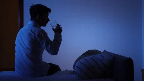 Young man drinking water in bed at night Stock Footage 317723578