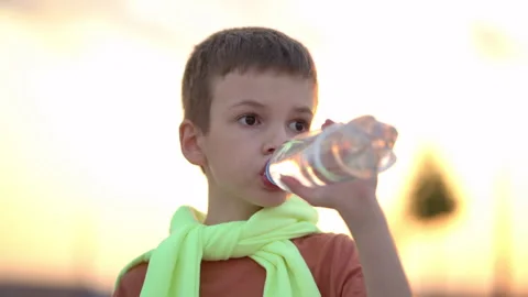 Young man drinking water from a plastic bottle in the city at sunset Vídeo Stock 202580590