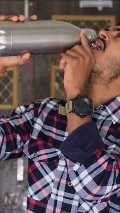 Young man drinking water from a stainless steel bottle 스톡 동영상 331354250