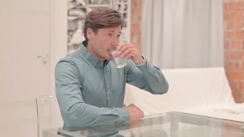 Young Man Drinking Water while Sitting at Home Video stock 238646273