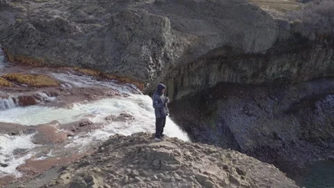 Young man drinking yerba mate standing at the edge of Salto del Agrio waterfall Stock Footage 315281008