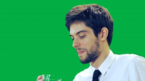 A  young man drinks and smiling at the camera - green screen Video stock 30438407