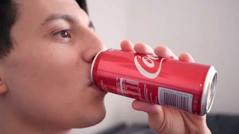 Young Man drinks Coca Cola from a Can sitting at Home relaxing Stock Footage 143804769