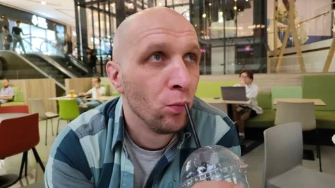 Young man drinks cocktail or juice from straw in food court of shopping center Vidéo 201636098