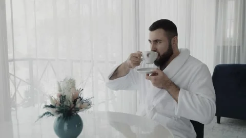 A young man drinks coffee and looks out the window. Stock Footage 313097996