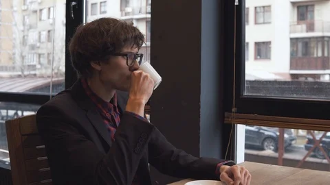 Young man drinks coffee in a cafe Stock Footage 86490727