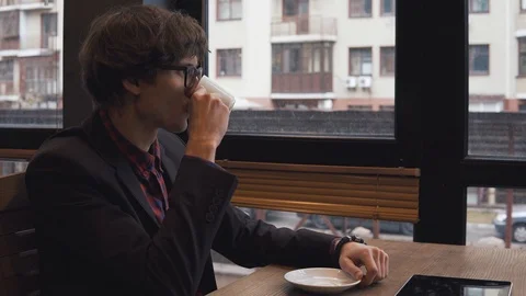 Young man drinks coffee in a cafe Stock Footage 86490733