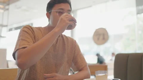 A young man drinks coffee at a relaxed cafe. Stock Footage 251974216