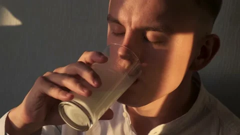 Young man drinks fresh milk from a glass Stock Footage 134472849