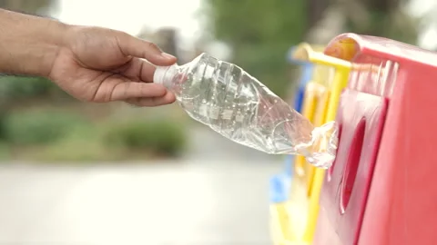 A young man drinks from plastic bottles and throws them into the trash. Video ab Stock Footage 153947334