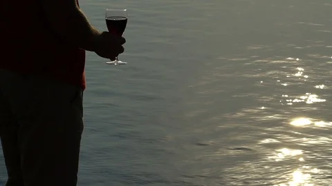 Young Man Drinks Red Wine From A Glass, Sunset By The Sea Stockbeeldmateriaal 96730548