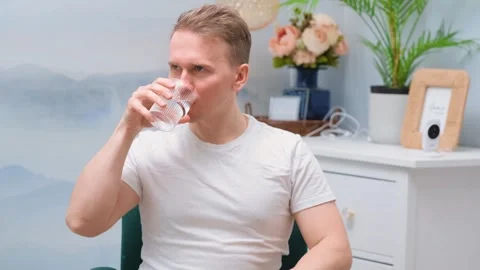 The young man drinks a tablet with water from a glass Stock Footage 303543388