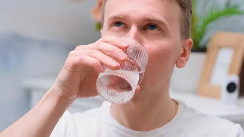 The young man drinks a tablet with water from a glass Stock Footage 303543400