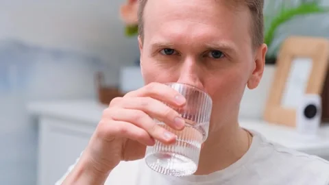 The young man drinks a tablet with water from a glass Stock Footage 303543407